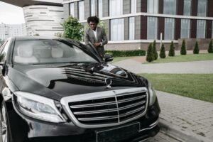 Confident man in suit next to a luxury car, embodying success in cityscape.
